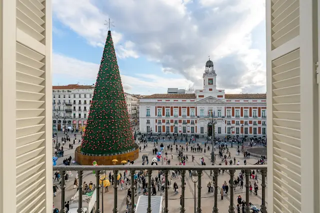 Giant Christmas tree at Puerta del Sol seen through shuttered window at La Fonda de los Príncipes