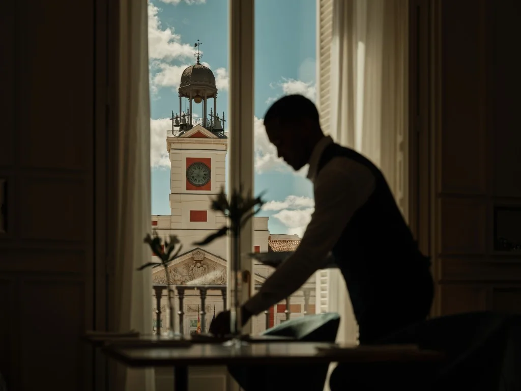 Silhueta de empregado a preparar mesa com o relógio da Real Casa de Correos ao fundo