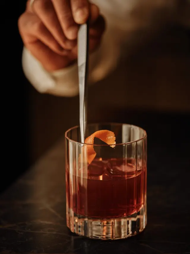 Close-up of a negroni being prepared with tongs at the bar of La Fonda de los Príncipes