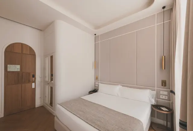 Cama con cabecero panelado y puerta de madera en arco en la habitación Deluxe Exterior
