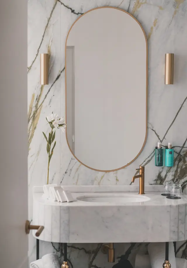 Lavabo de mármol con espejo ovalado de marco dorado y amenities Rituals en el baño de la Deluxe Lateral Sol
