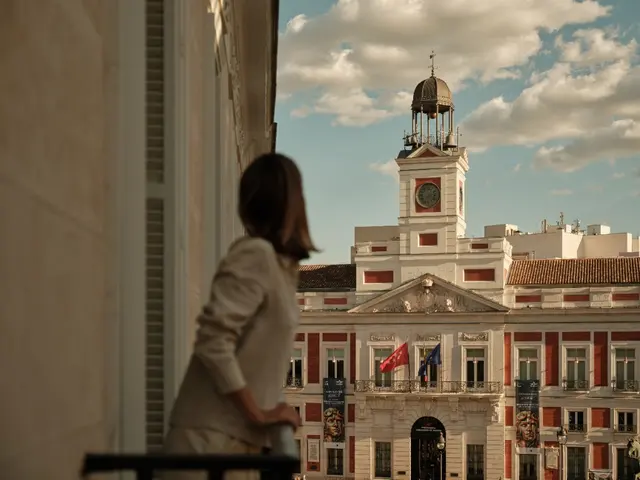 Woman gazing at the Real Casa de Correos from the balcony of the Deluxe Sol View room at La Fonda de los Príncipes
