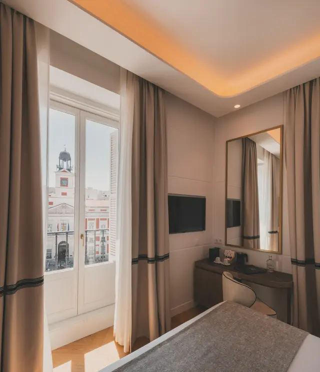 Ventana con vistas al reloj de la Real Casa de Correos junto al escritorio y el espejo de la Deluxe Vista Sol
