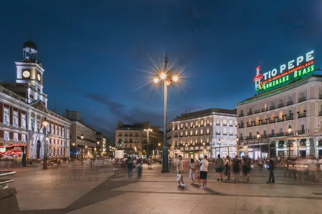 Plaza de la Puerta del Sol de noche, con el reloj de la Real Casa de Correos y el cartel Tío Pepe