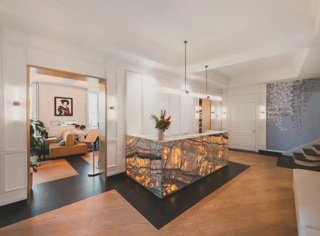 Hotel reception with an illuminated marble desk and parquet flooring