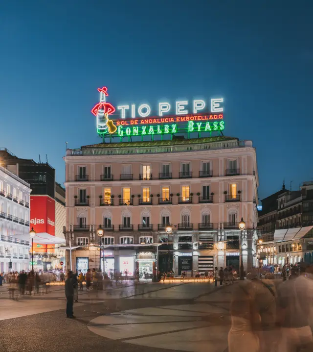 Tío Pepe building with its sign lit up at night on Puerta del Sol, home of La Fonda de los Príncipes