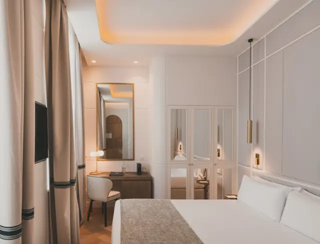 Cama, escritorio con espejo y armario junto a lámparas colgantes doradas en el Estándar Interior