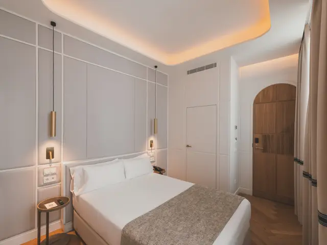 Cama doble con lámparas colgantes y puerta de madera en arco en el Estándar Interior