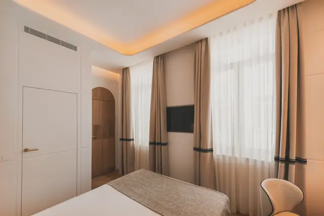 Cama frente a la ventana con cortinas, Smart TV y puerta en arco en la habitación Estándar Interior