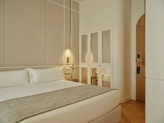 Double room with upholstered headboard, mirrored wardrobe and arched wooden door