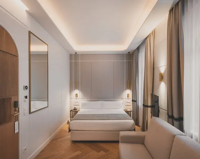 Junior Suite Interior Familiar con cama, sofá, puerta en arco y espejo bajo una iluminación indirecta