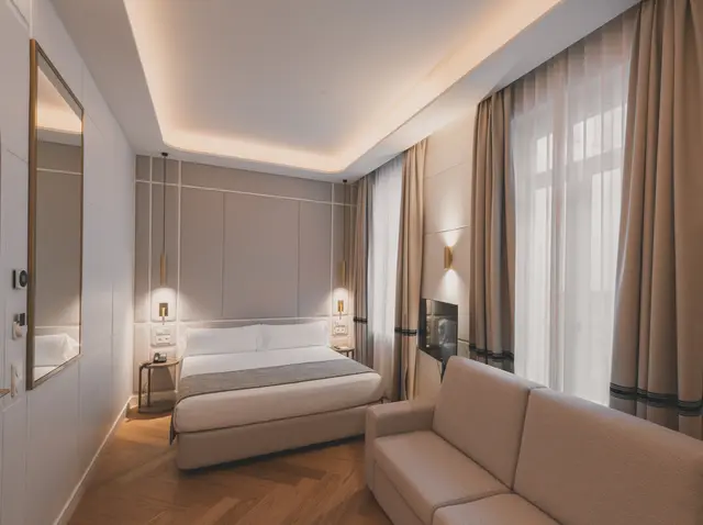 Cama y sofá junto al ventanal con cortinas en la Junior Suite Interior Familiar