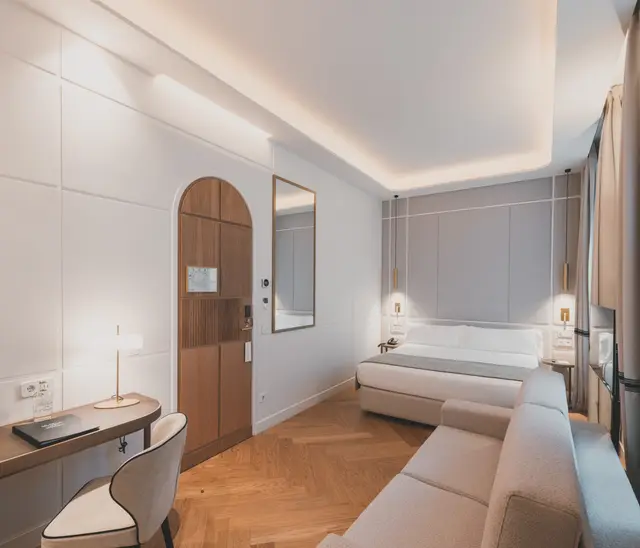 Puerta en arco, escritorio y sofá cama con la cama al fondo en la Junior Suite Interior Familiar