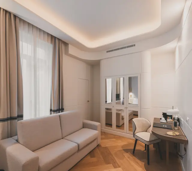 Sofá cama, escritorio y armario de espejos junto al ventanal en la Junior Suite Interior Familiar