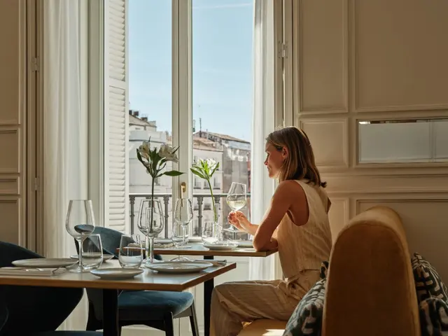 Woman enjoying a glass of wine by the window in natural light at the restaurant of La Fonda de los Príncipes