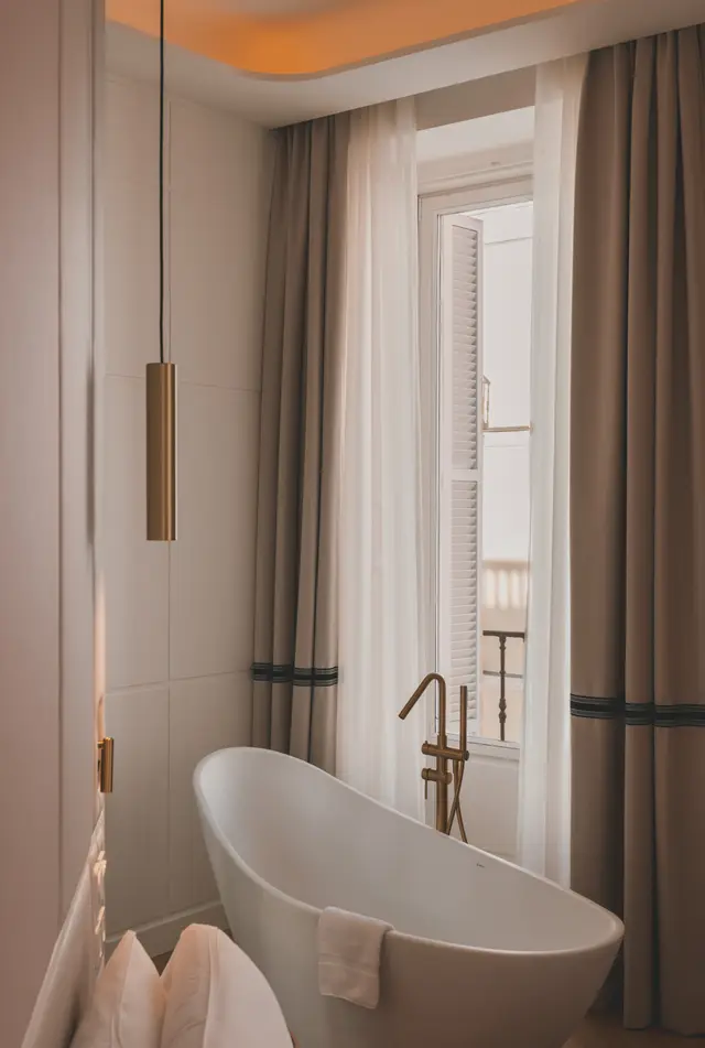 Bañera exenta con grifería dorada junto a la ventana de la Premium Corner con bañera