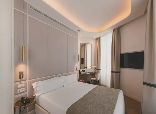 Cama con cabecero tapizado, apliques dorados, Smart TV y escritorio en la Premium Corner con ducha