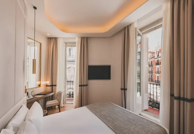 Cama, Smart TV y escritorio junto a la puerta del balcón en la habitación Premium Corner con ducha