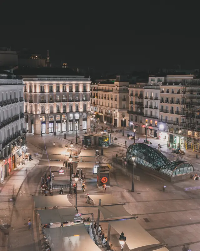 Vista nocturna de la plaza de la Puerta del Sol con los edificios iluminados y los toldos