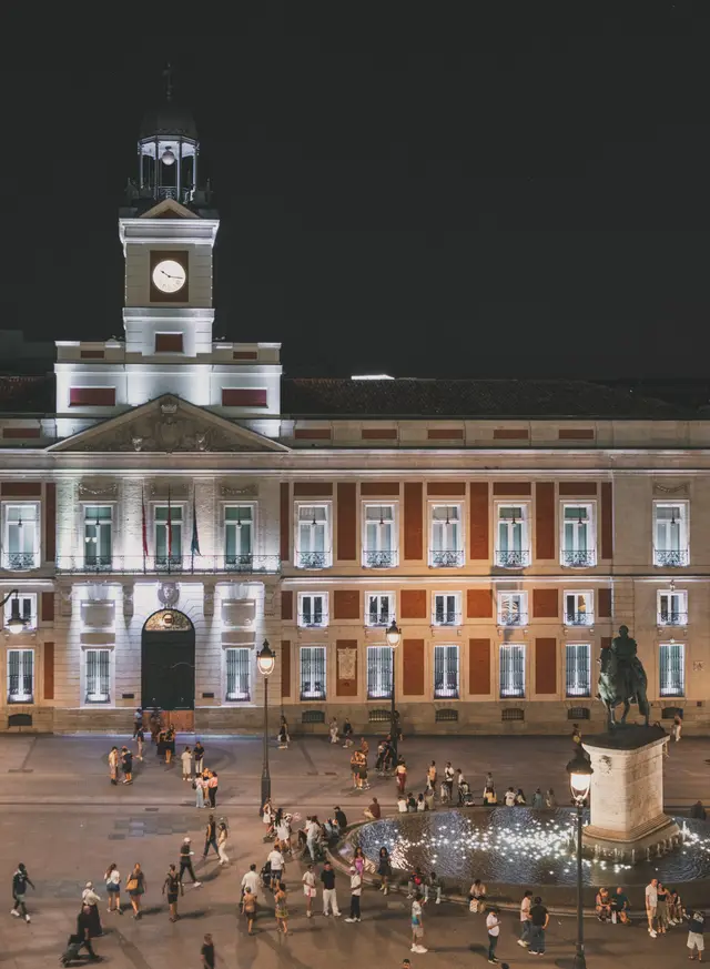 La Real Casa de Correos iluminada de noche con la estatua de la plaza en primer plano