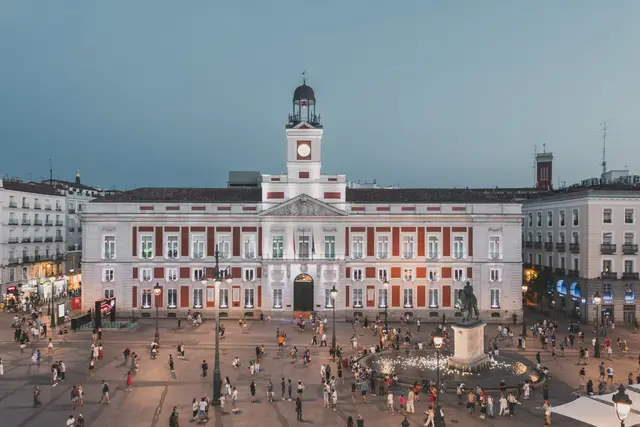 La Real Casa de Correos y la plaza llena de gente en la hora azul, vistas desde La Fonda de los Príncipes